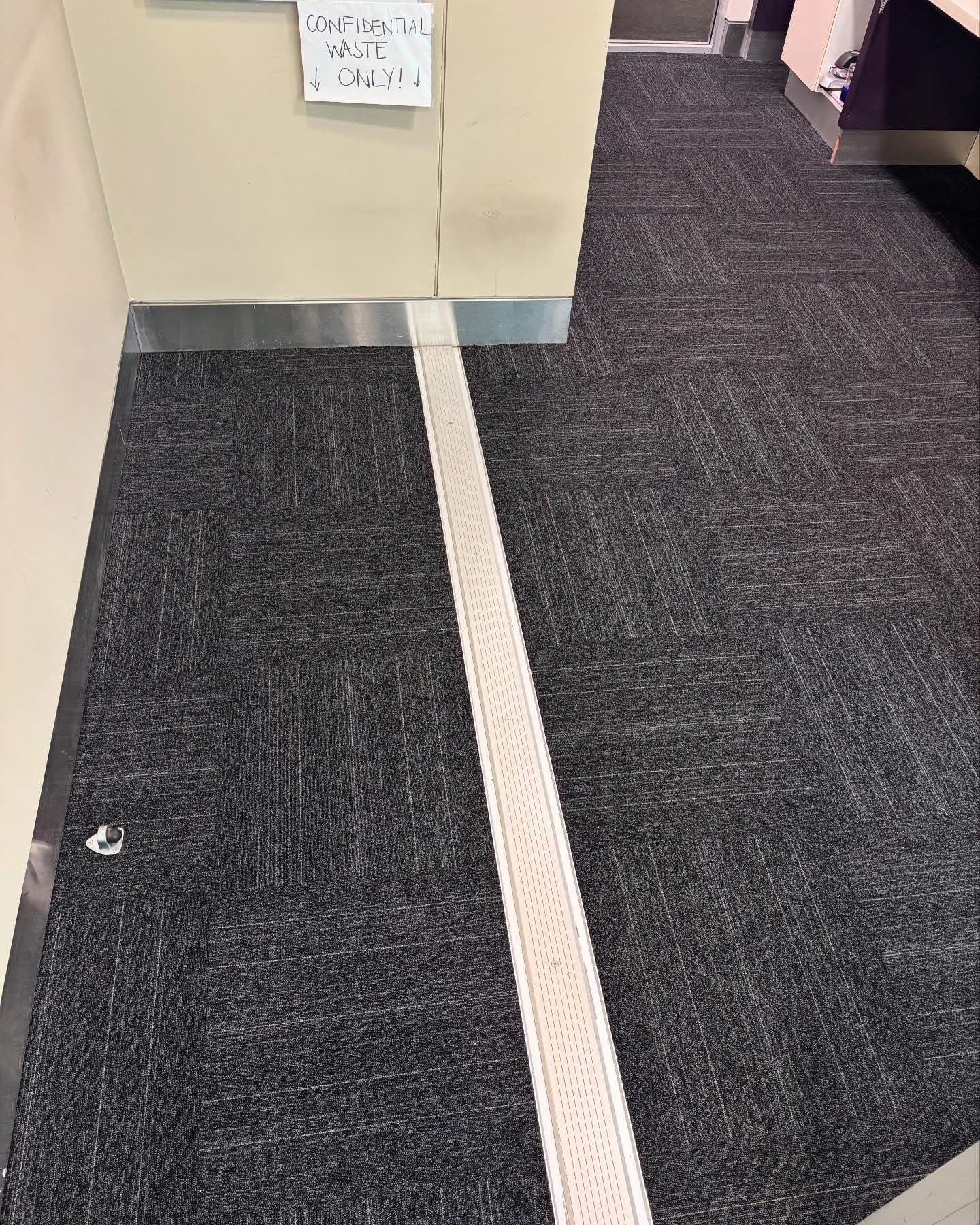 Carpet tile join with aluminium transition strip at office doorway