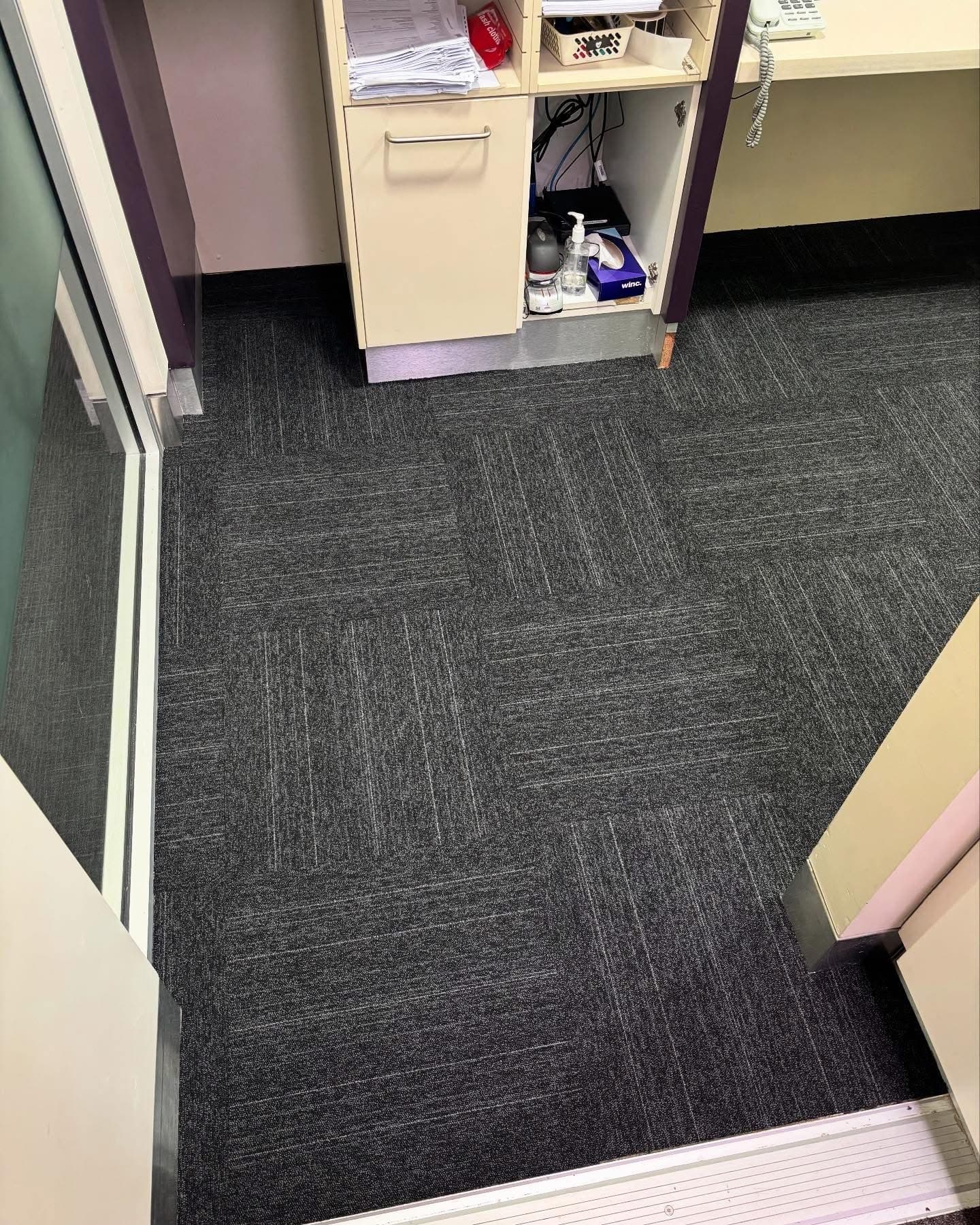 Office entry area with charcoal commercial carpet tiles, viewed from above
