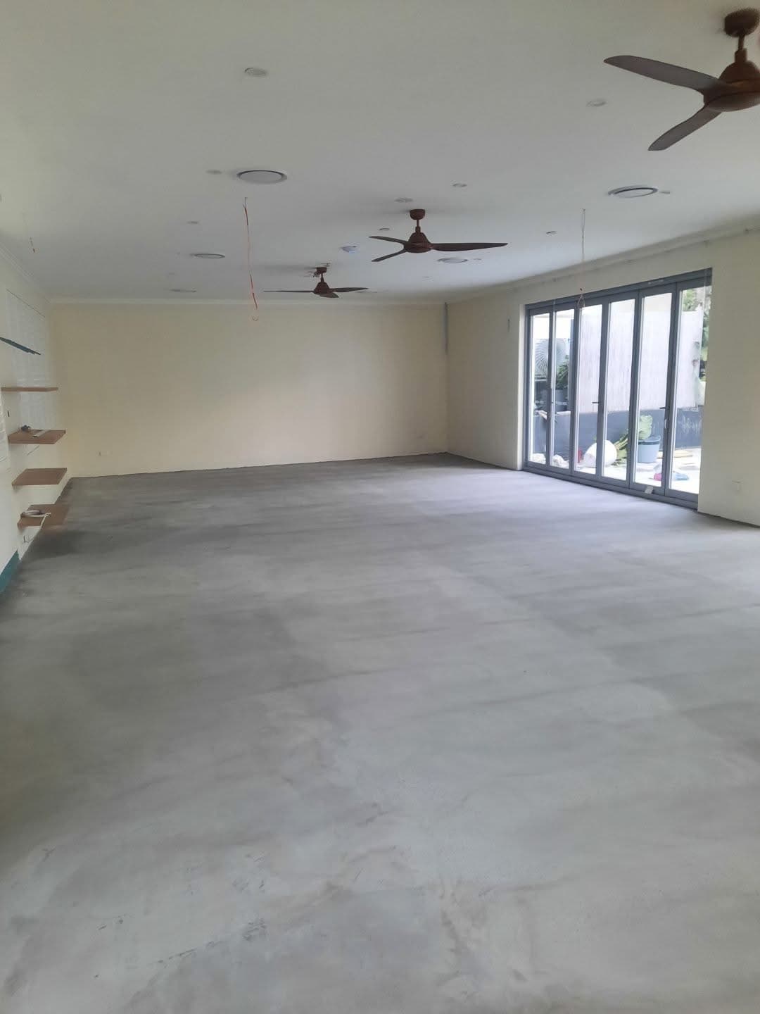 Common area before installation showing bare concrete slab with ceiling fans