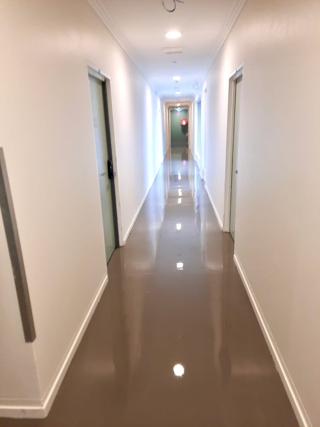 Hostel corridor with glossy vinyl plank flooring and recessed lighting