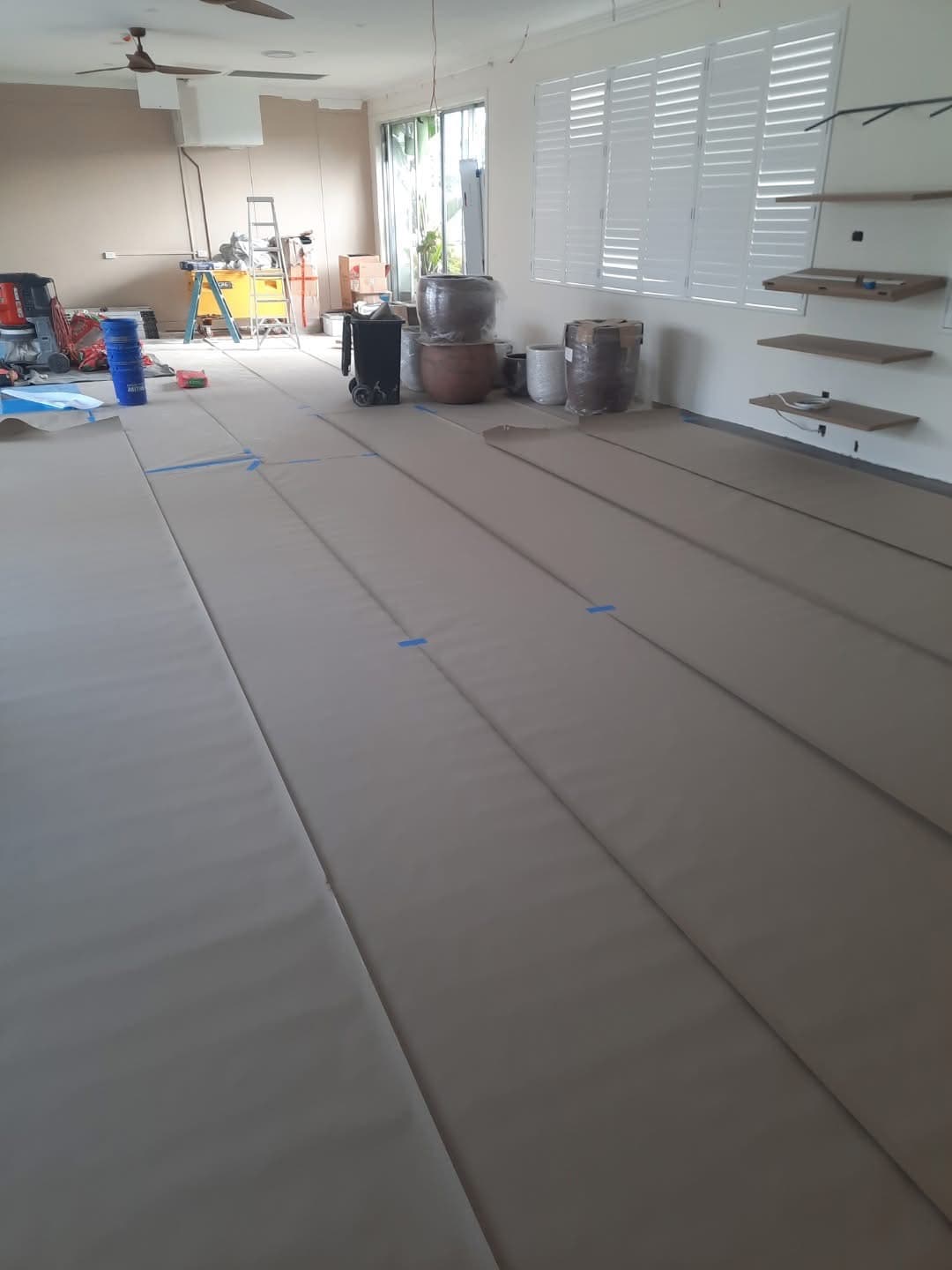 Installation in progress — vinyl plank rolls laid out across the large common area subfloor