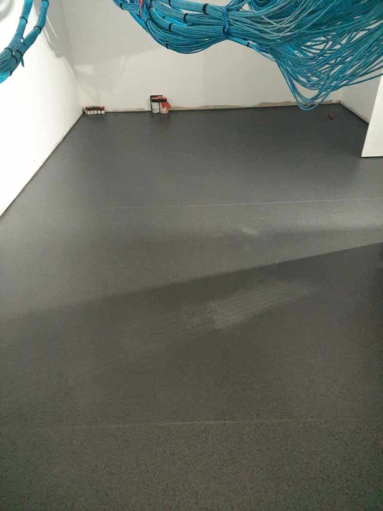Dark charcoal carpet installed in a fire station room with cabling still being routed above
