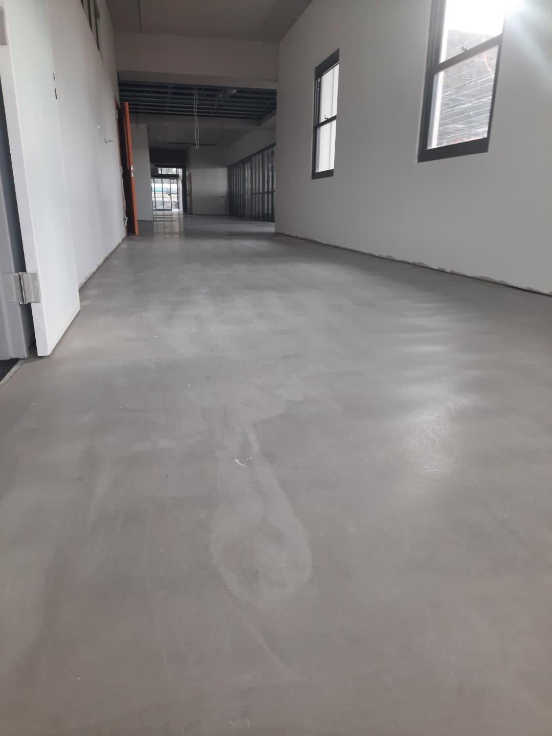 Wide corridor with cured self-levelling compound ready for flooring installation