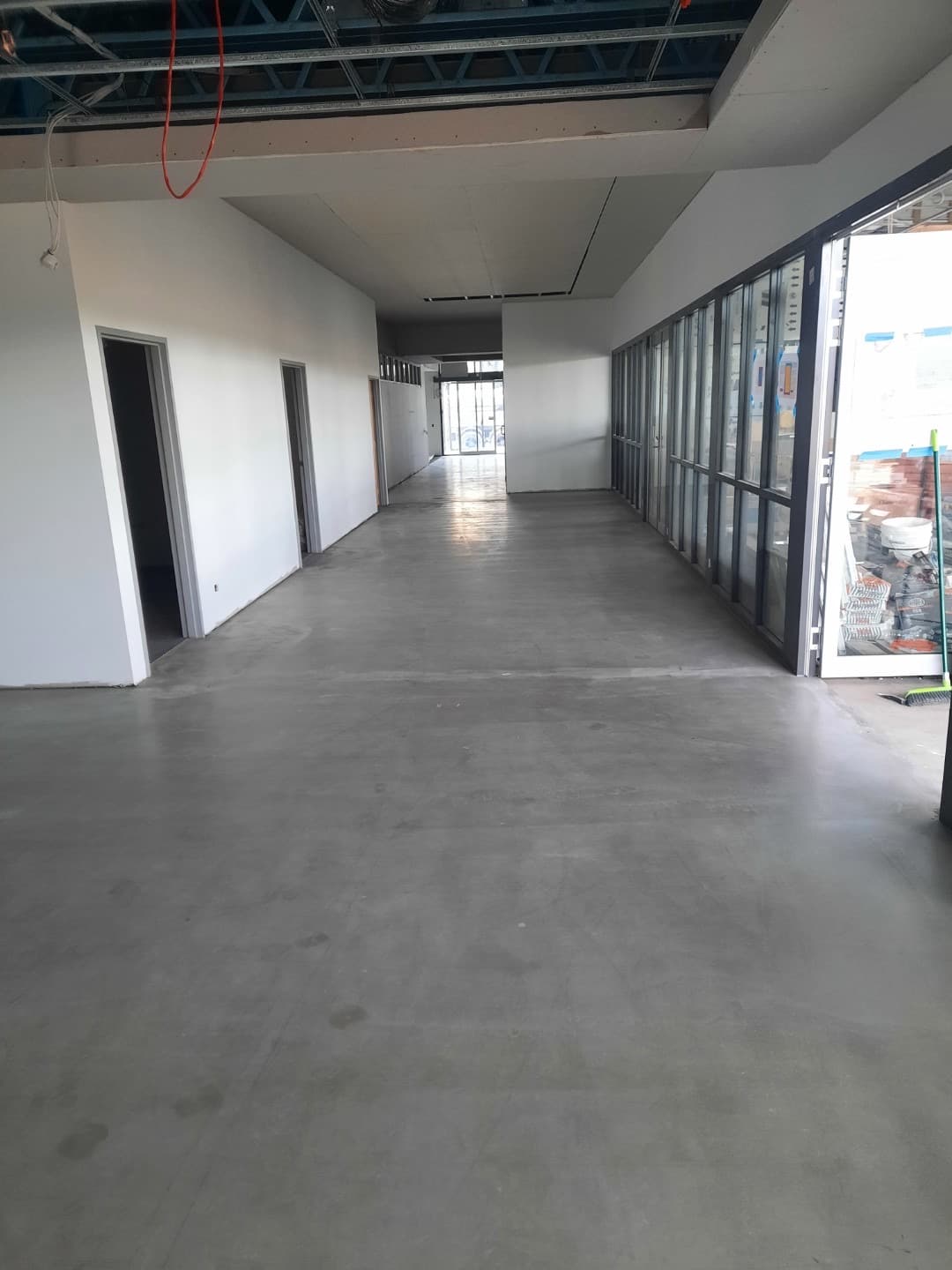 Long corridor with concrete subfloor and floor-to-ceiling glazed exterior wall