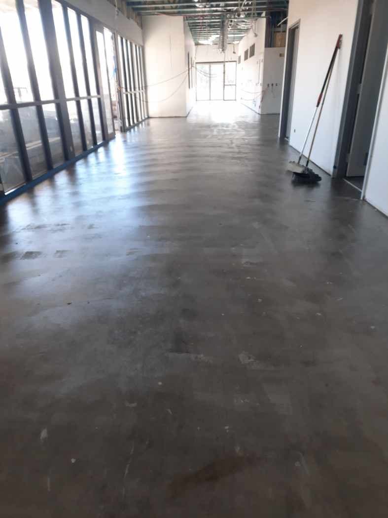 Main hall with raw concrete subfloor alongside large glazed windows during construction