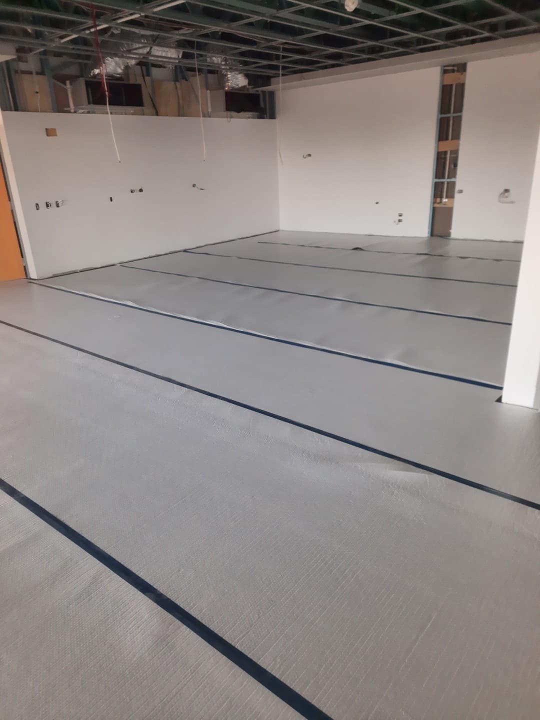 Sheet vinyl laid across a large room with exposed ceiling structure above