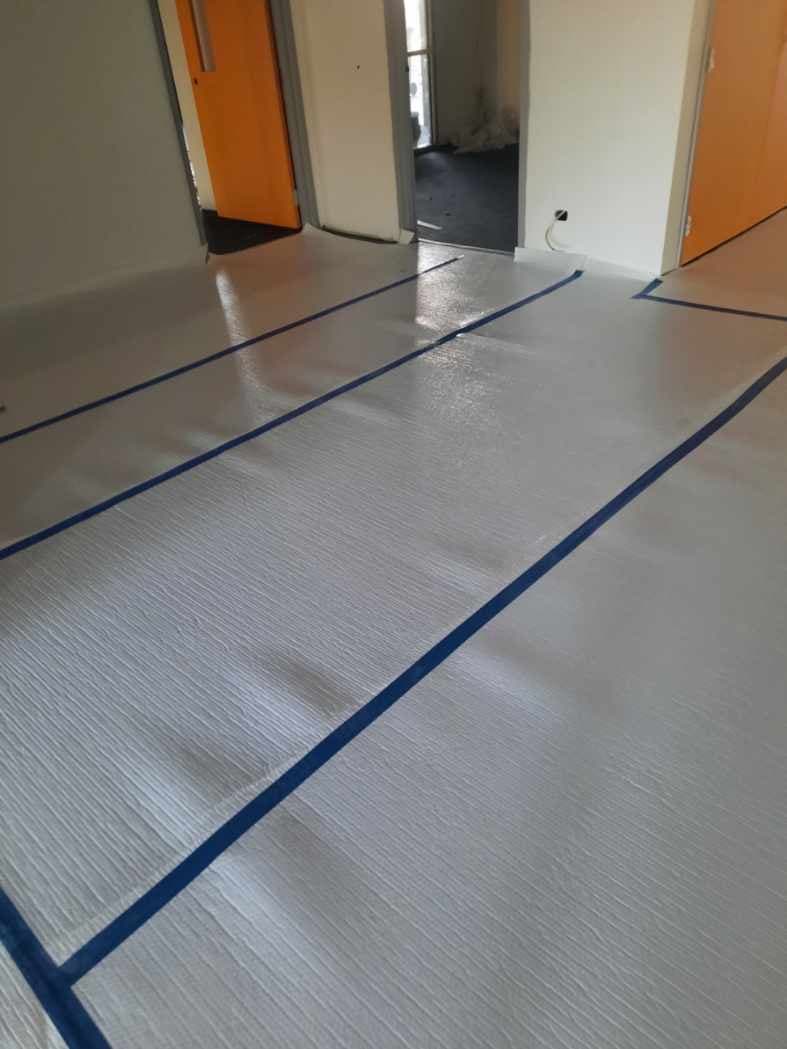 Sheet vinyl with blue seam tape being installed in an office room
