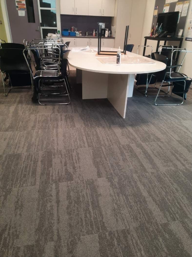 Conference room with charcoal carpet tiles and round white meeting table — Moree office