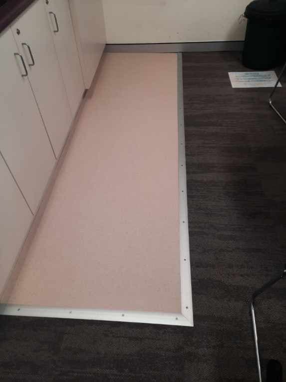 Close-up of beige sheet vinyl flooring installed beneath kitchenette cabinetry