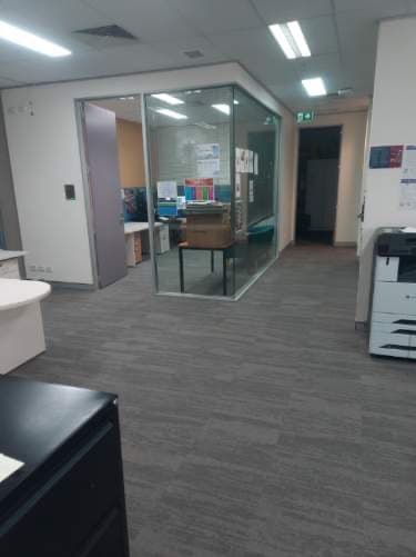 Office interior with carpet tile floors and glass-walled meeting pod