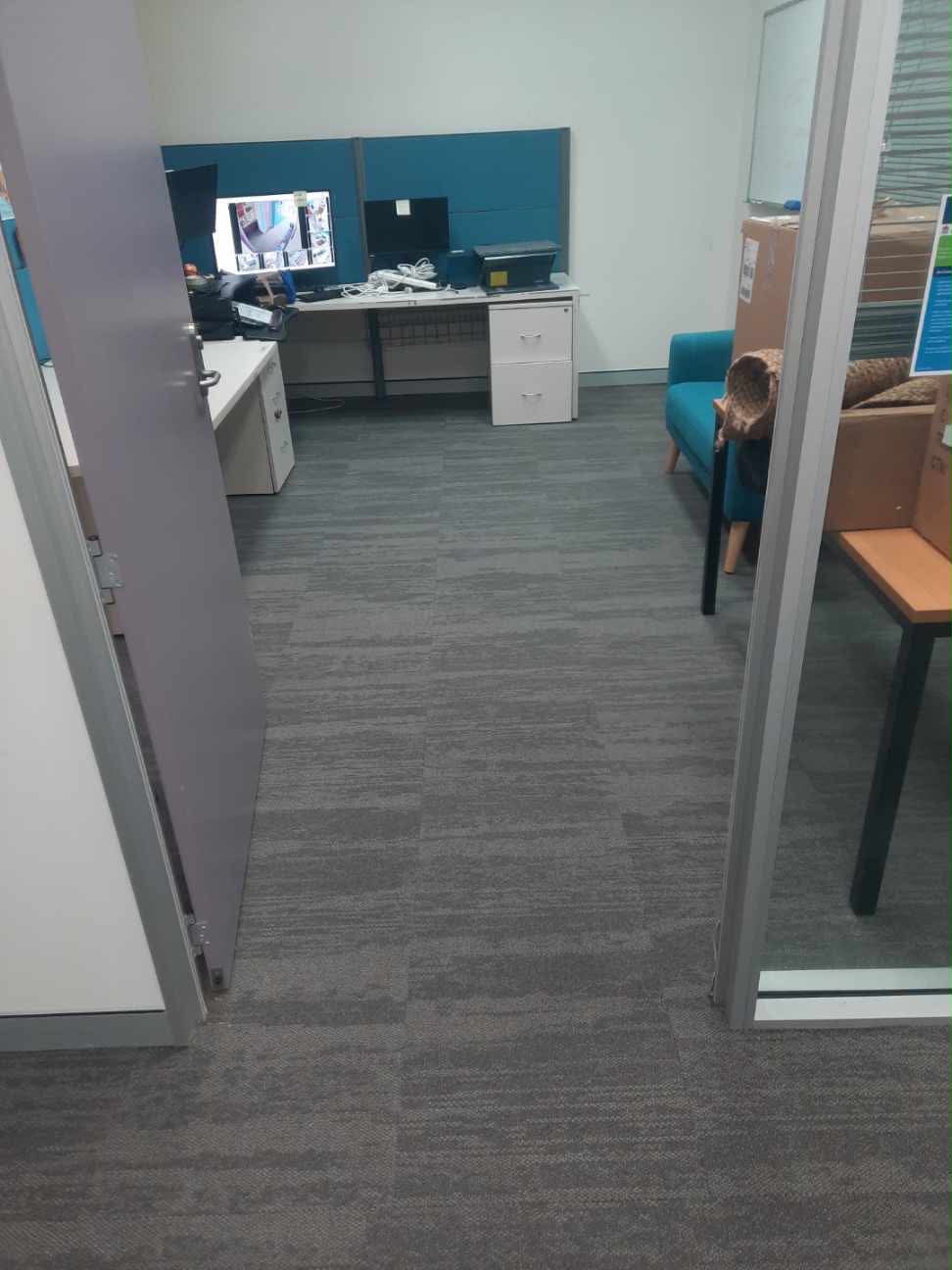 Office room entry with carpet tiles, teal cubicle screens and waiting area chairs