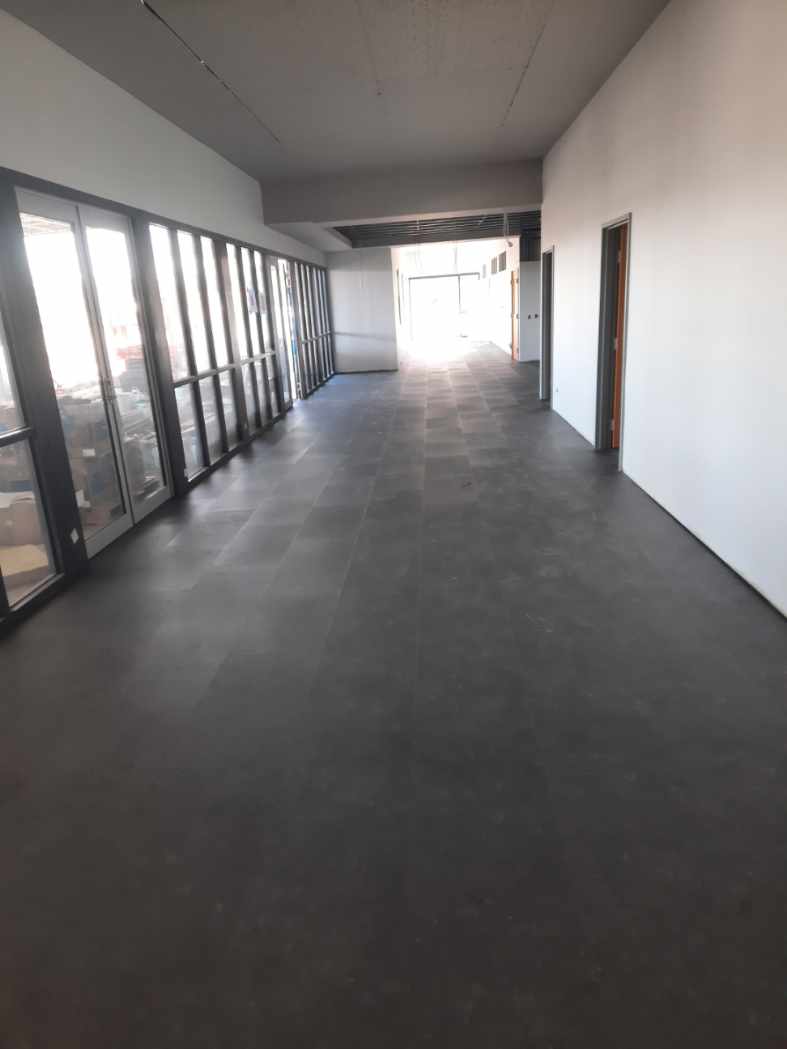 Completed corridor with dark grey Gerflor LVT Creation tiles and full-height glass facade — Narrabri Fire Station