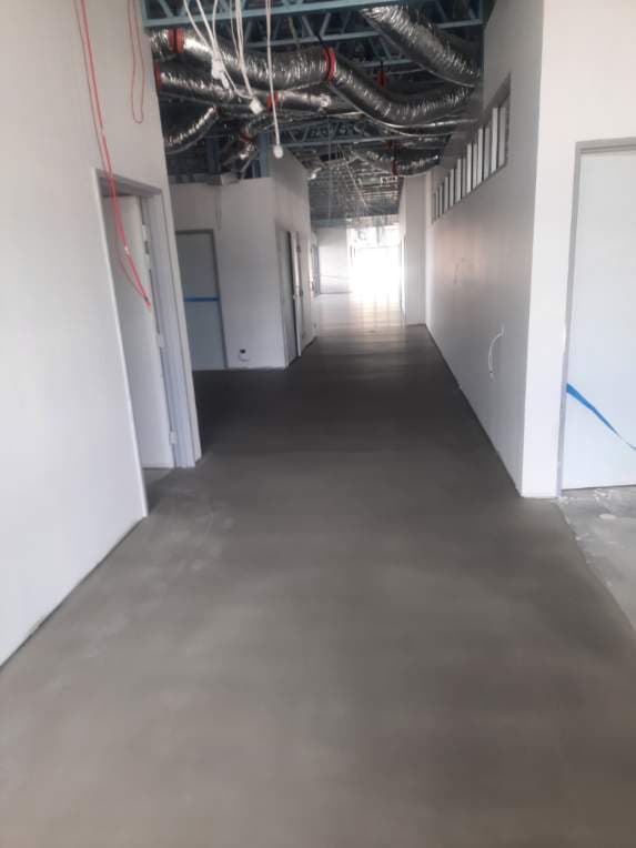 Corridor with concrete screed preparation underway before LVT installation