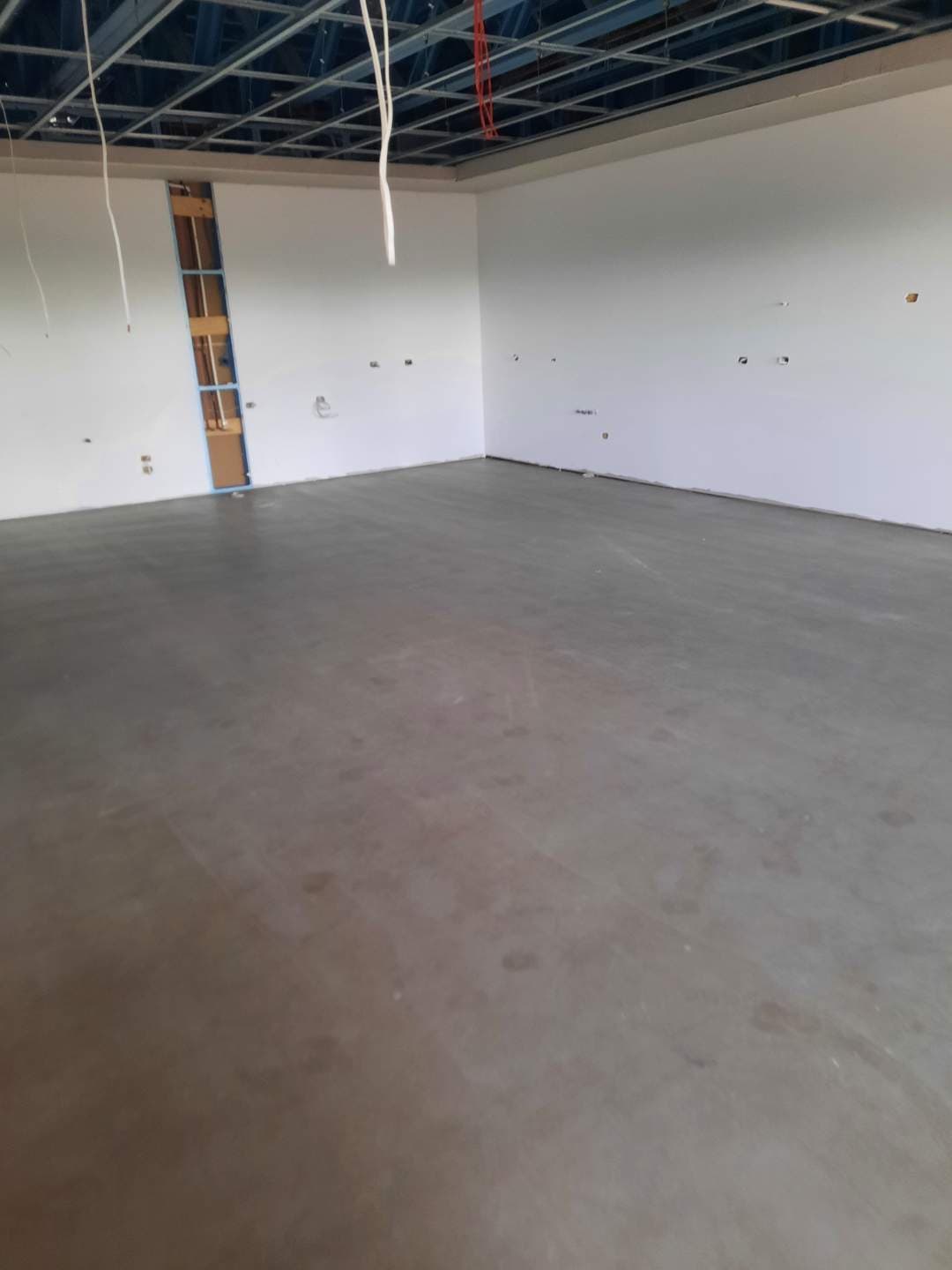 Open room with bare concrete screed floor before installation