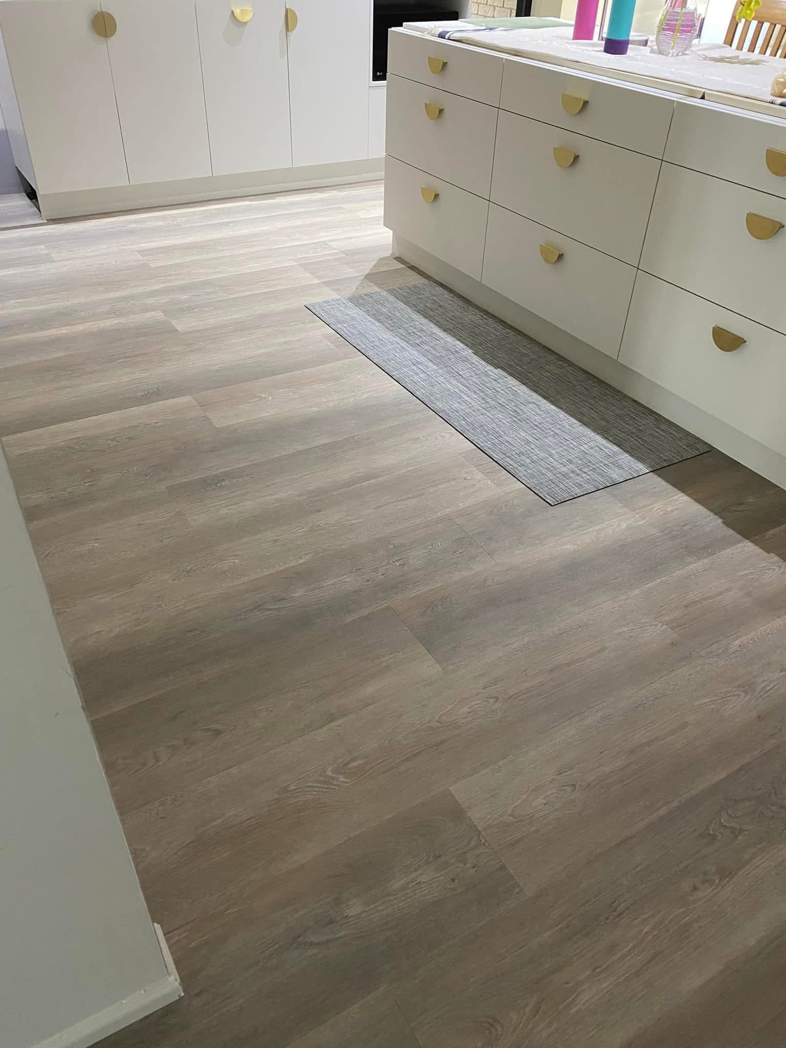 Kitchen with white cabinetry and gold hardware over new vinyl plank flooring