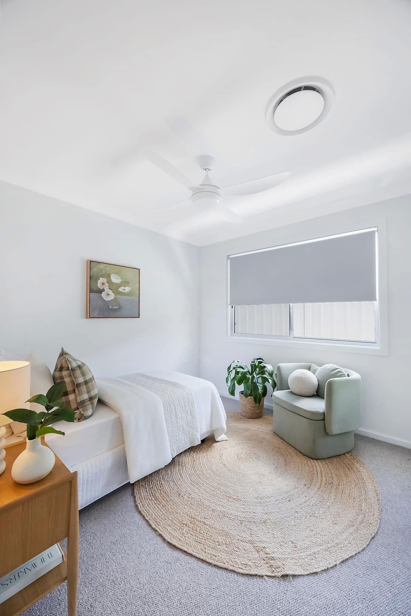Third bedroom with grey carpet, jute rug, green armchair and floral artwork