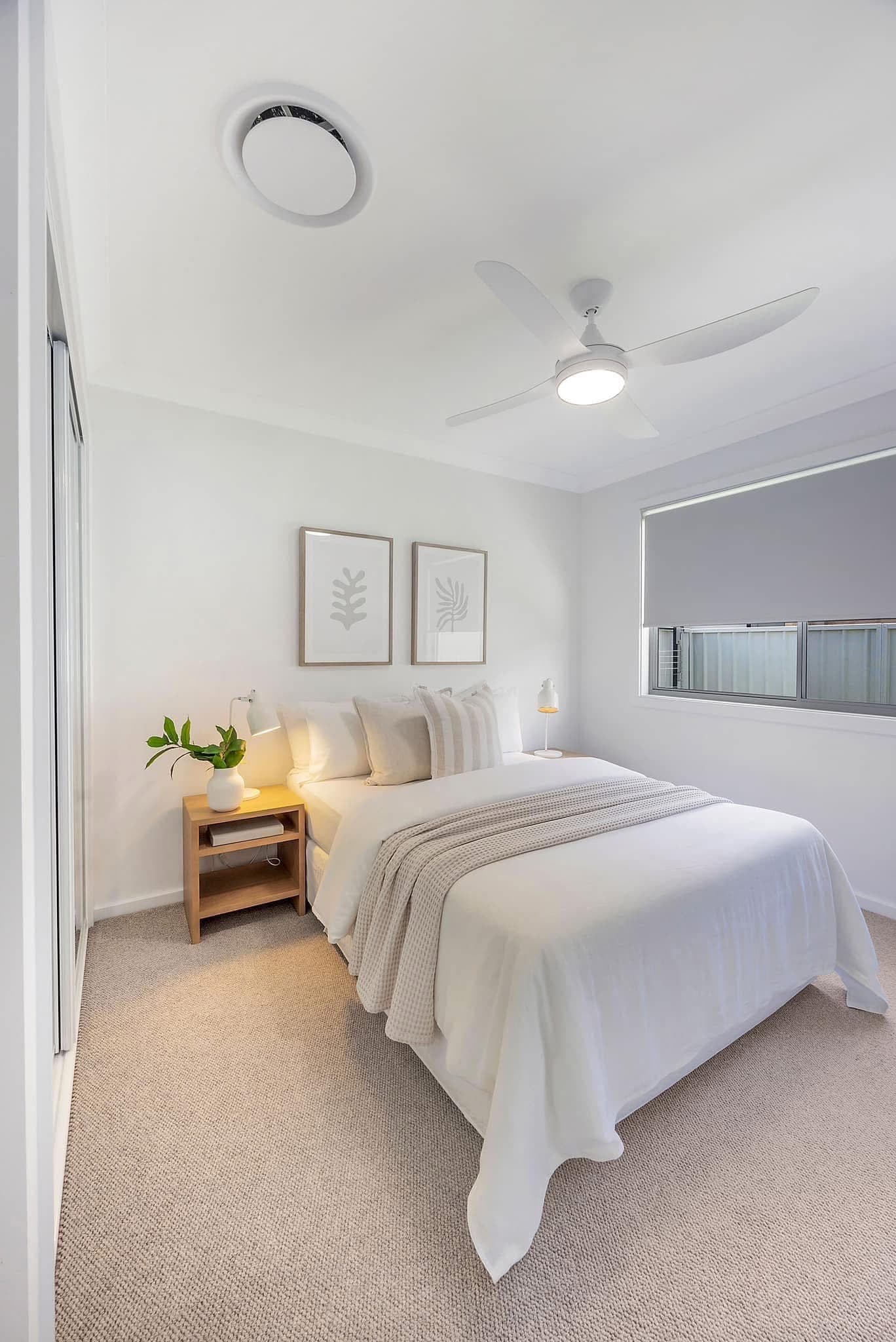 Second bedroom with light carpet, botanical framed prints and warm bedside lighting
