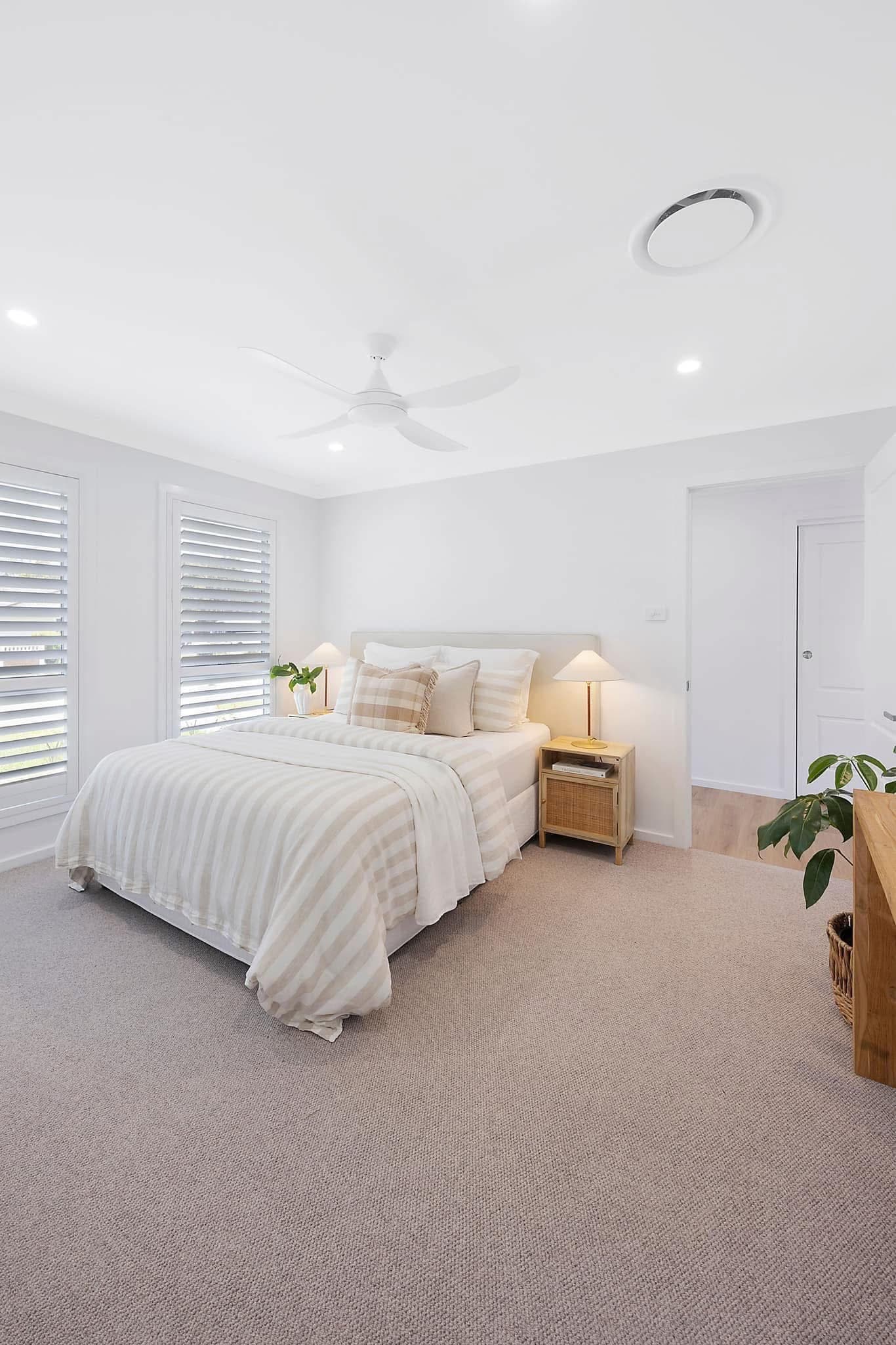 Master bedroom with light sand carpet, plantation shutters and white linen bedding