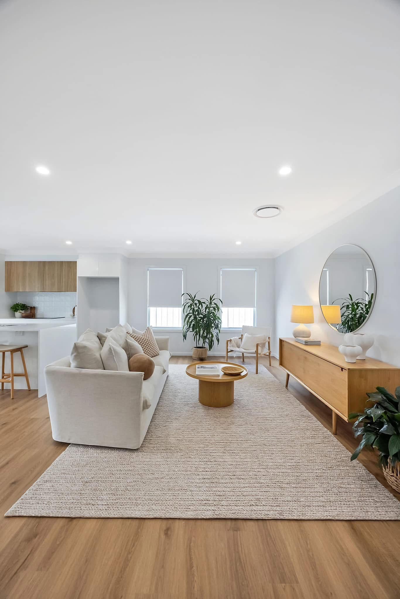 Bright open-plan living and dining area with light blonde vinyl plank flooring, white sofa and timber sideboard — Adamstown
