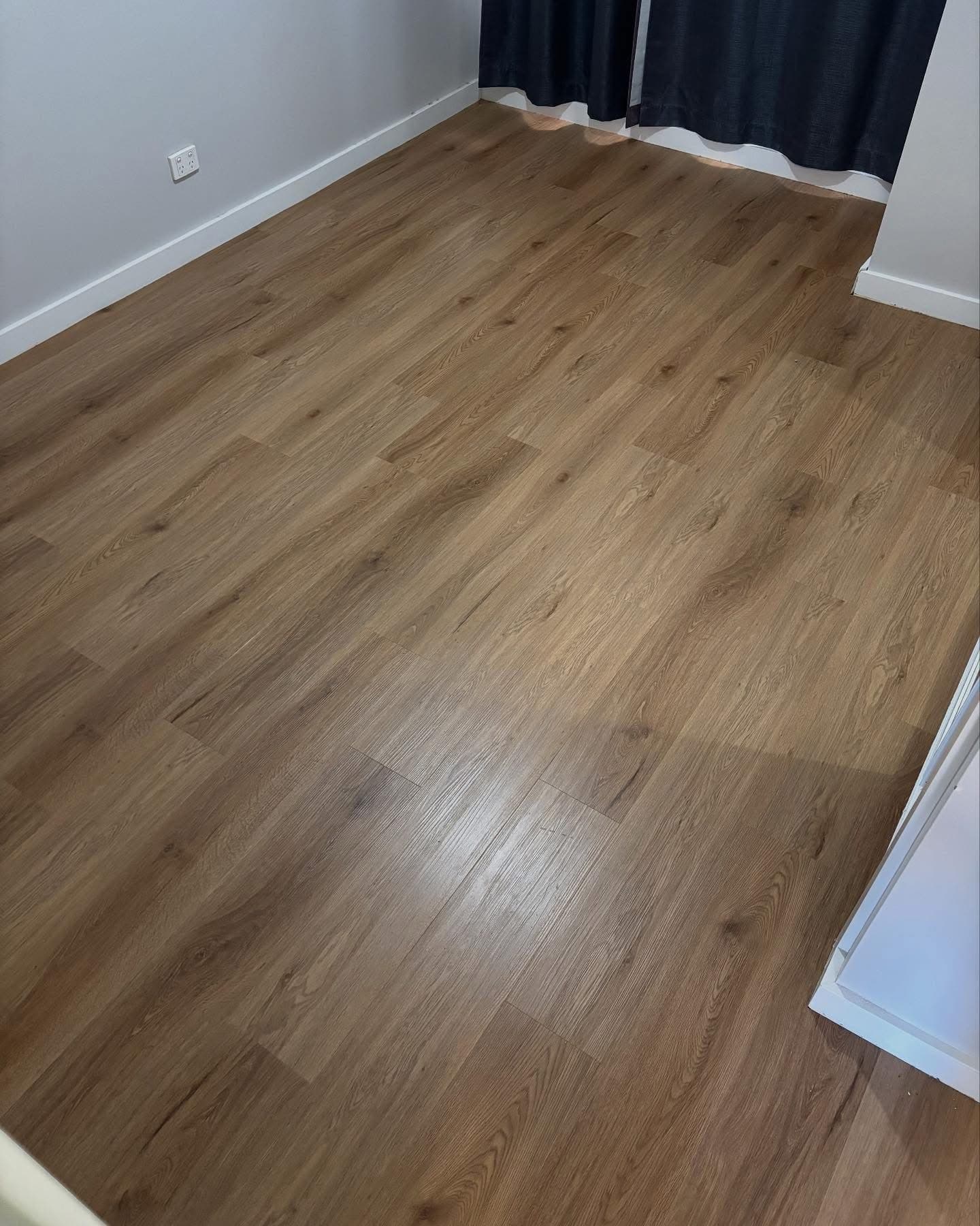 Bedroom with new warm oak vinyl plank flooring and dark curtains