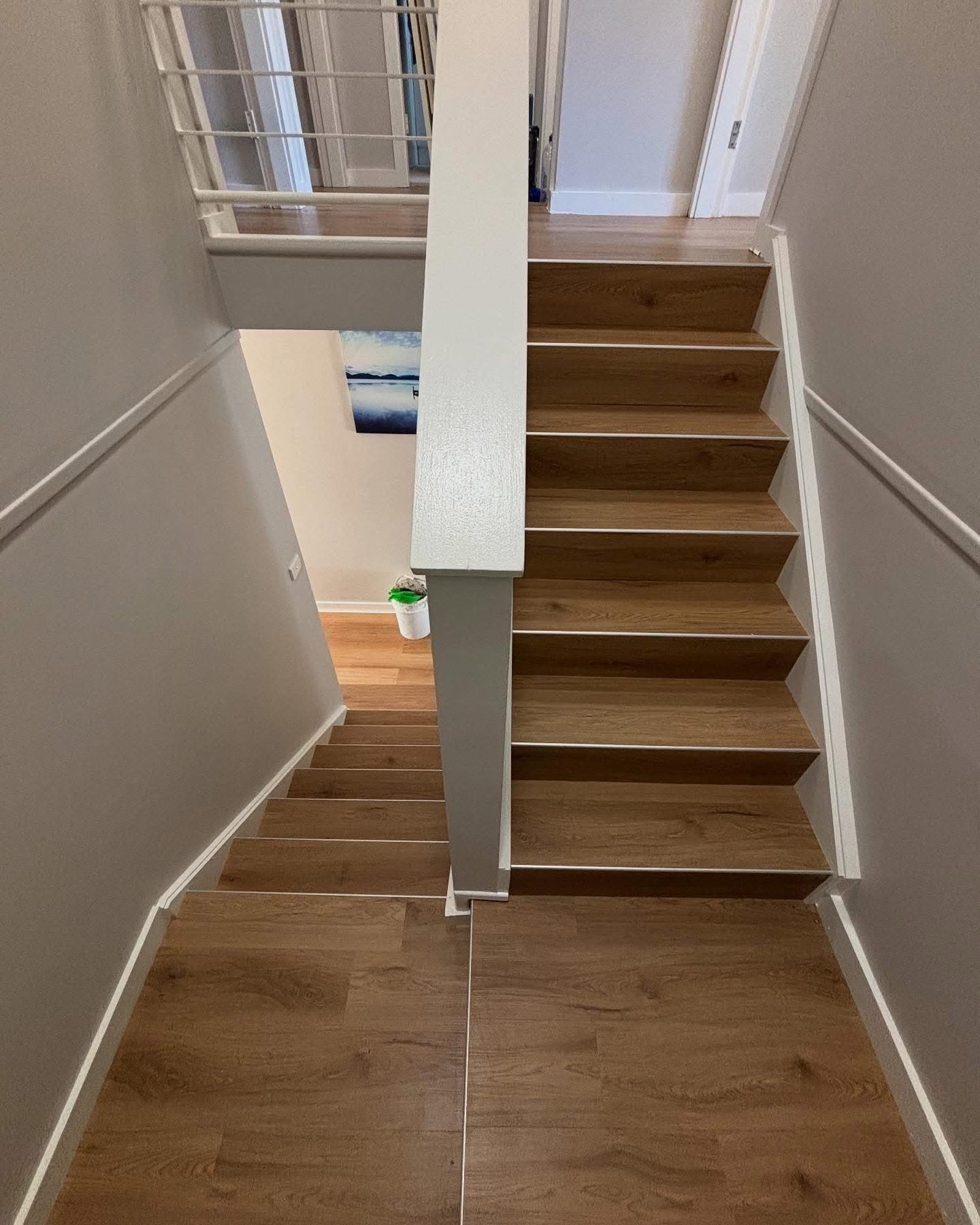 Top-down view of completed staircase with warm oak vinyl plank and white balustrade