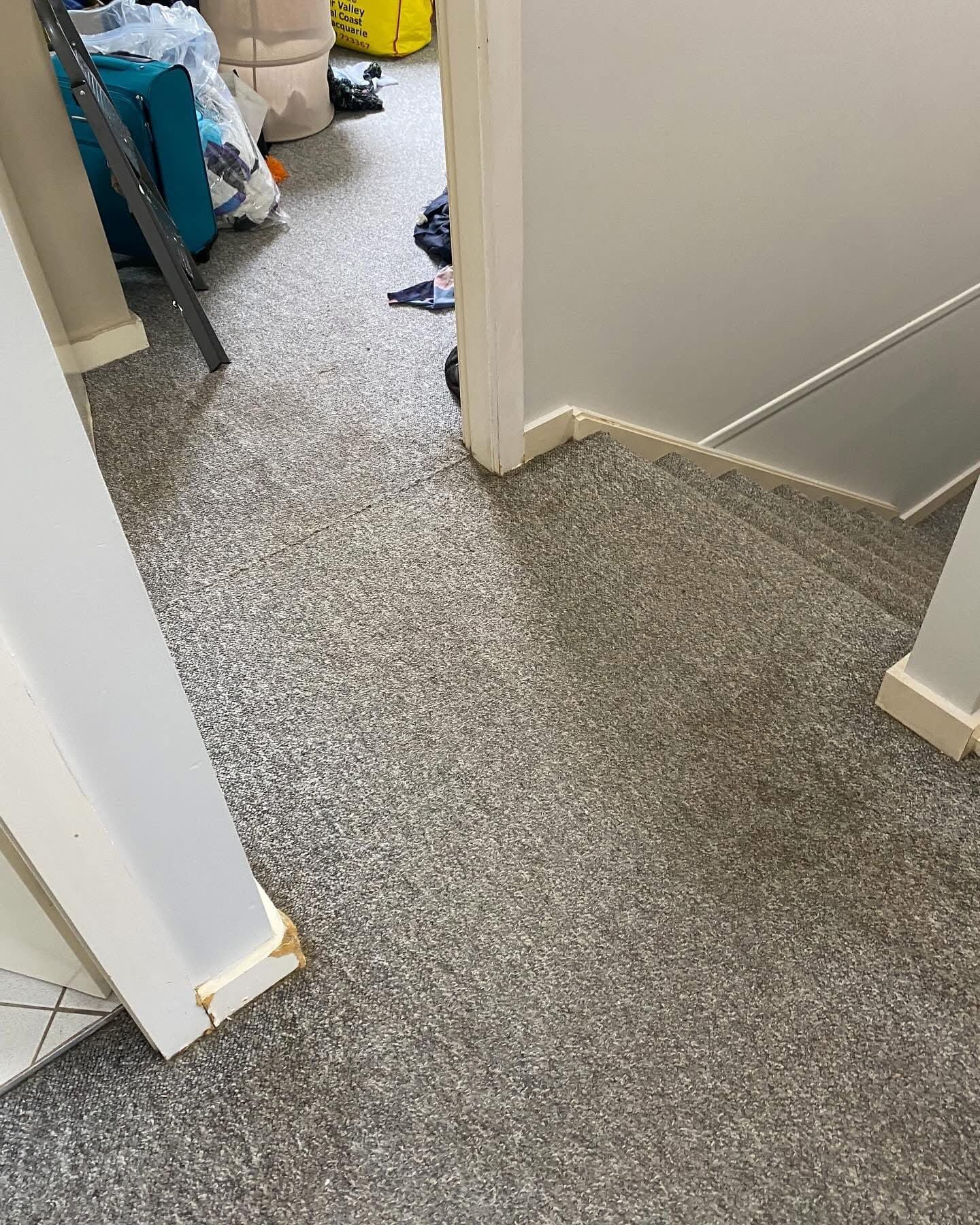 Before: upstairs hallway with grey carpet during demolition