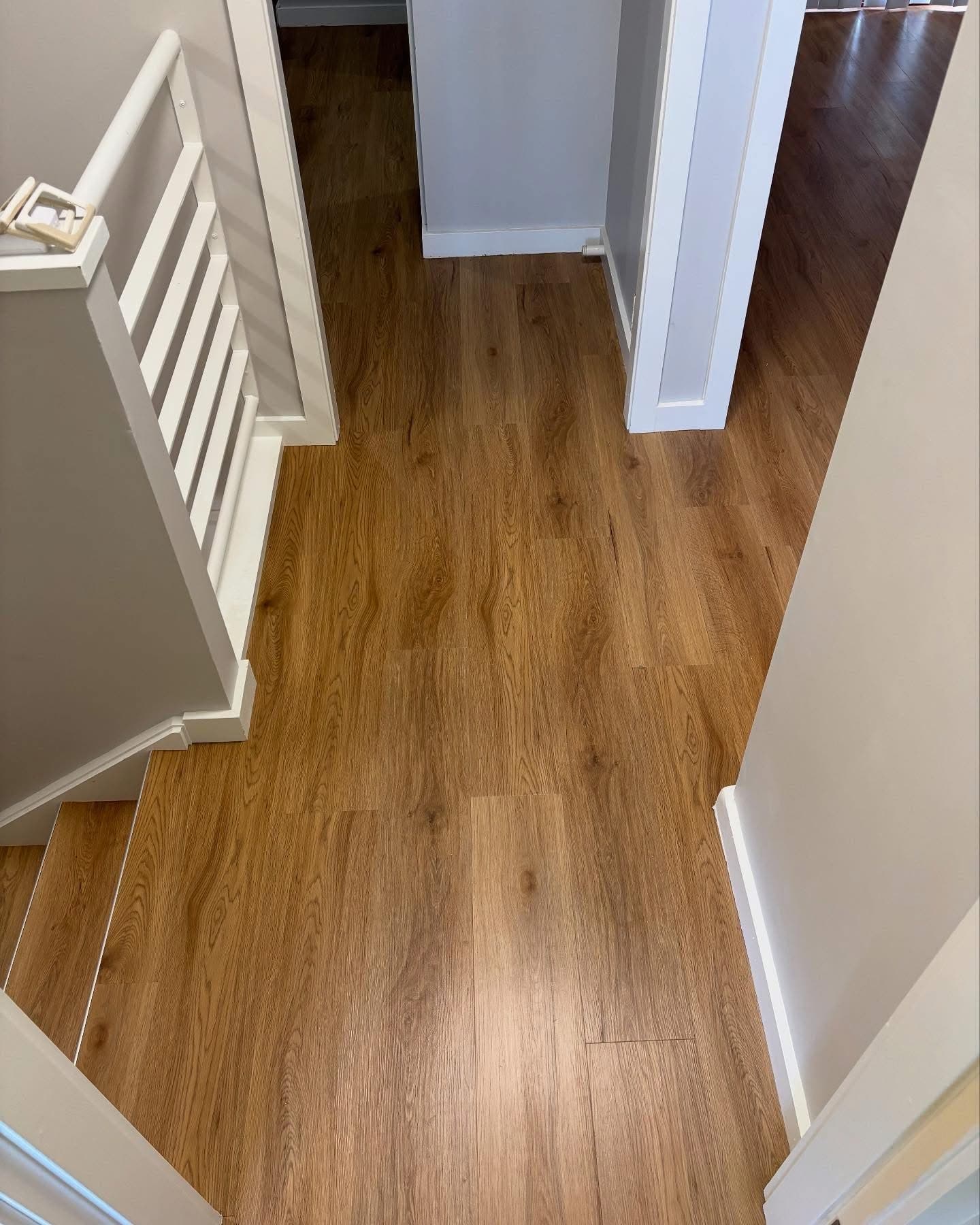 Upstairs landing with vinyl plank flooring beside white balustrade at top of stairs