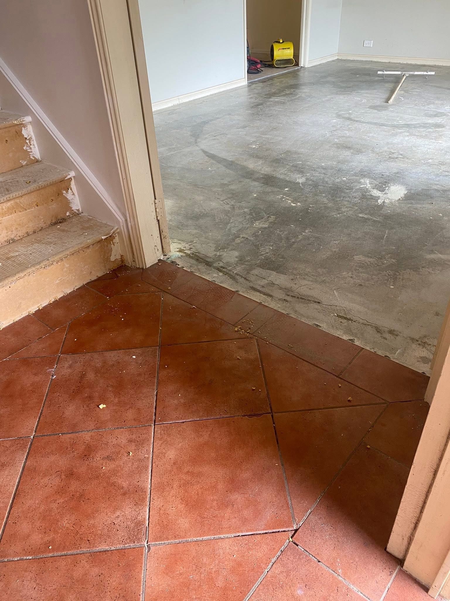 Before: old red terracotta diagonal tiles in the entry foyer with stripped concrete subfloor beyond
