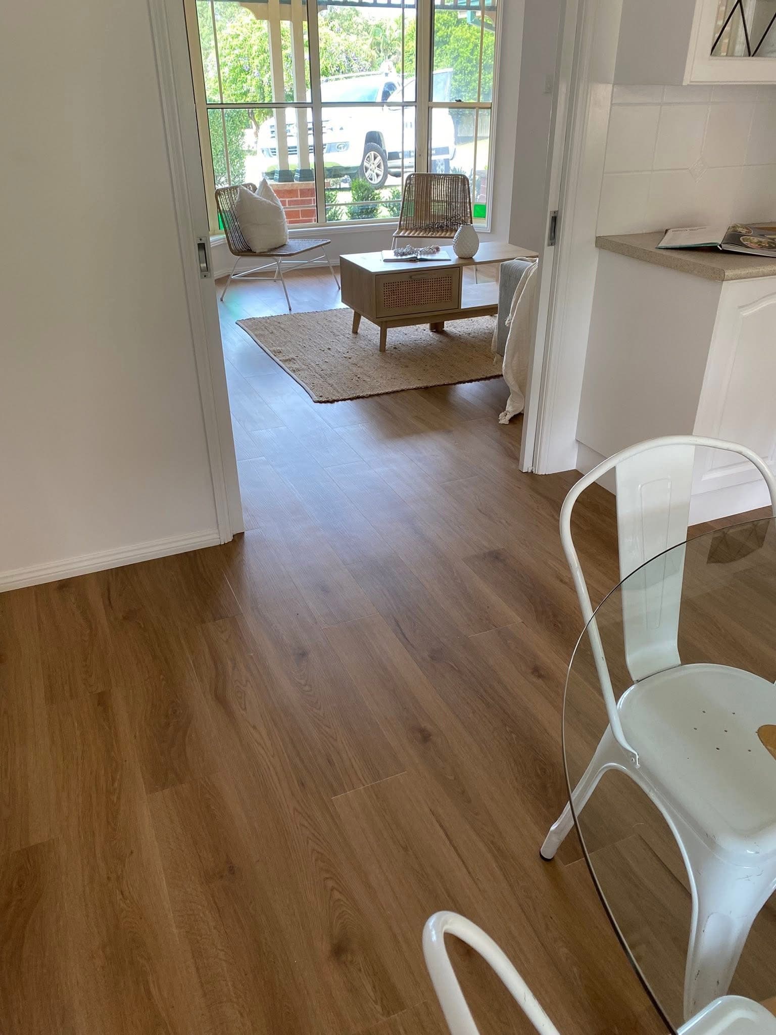 Secondary living area with warm vinyl plank flooring through to bay window with garden view