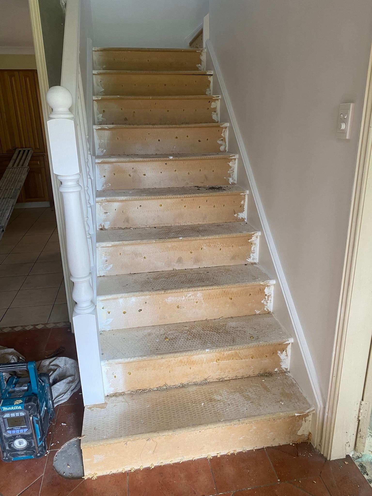 Before: staircase stripped of old carpet showing raw timber treads during demolition