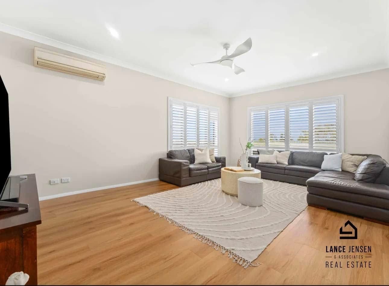 Bright living room with warm oak vinyl plank flooring, plantation shutters and leather sofas — Belmont North